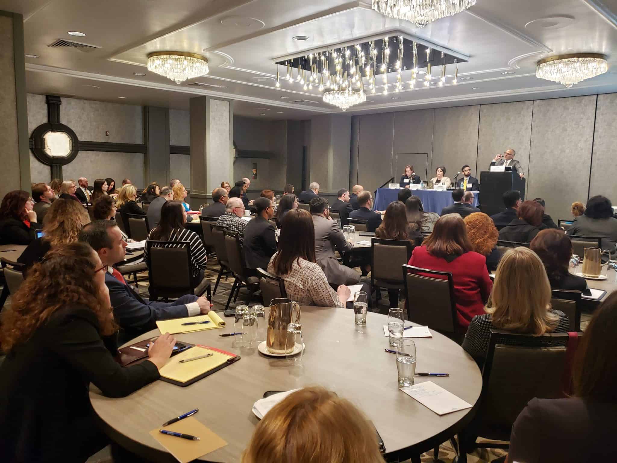 Conference attendees listen to a panel discussion during a consumer protection and compliance-focused session.