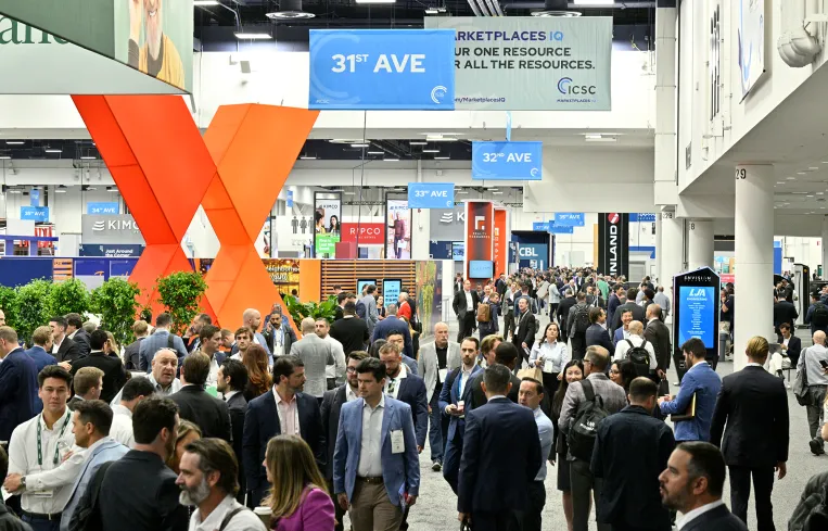 A busy exhibition hall at ICSC+U.S. Law, with attendees networking and exploring industry exhibits.