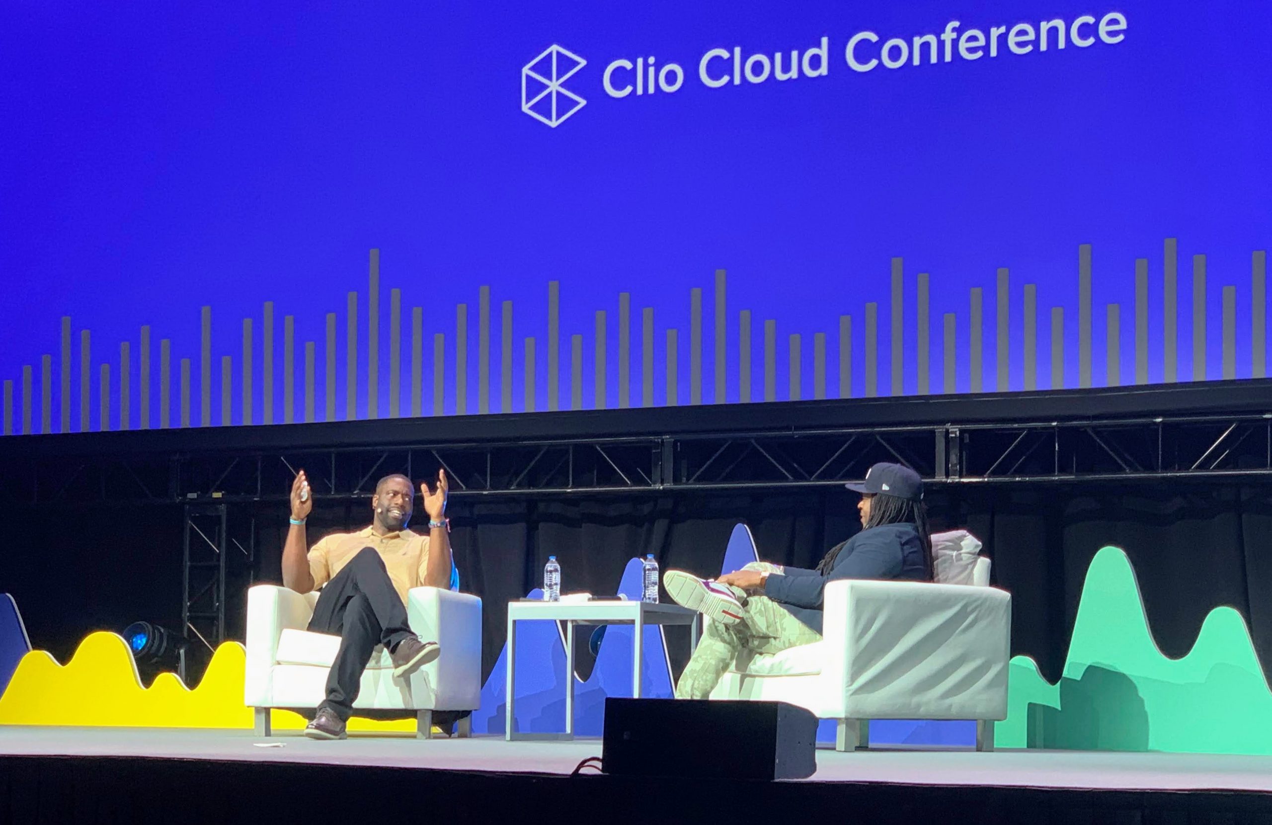 Deux intervenants conversent de manière animée sur scène à la Clio Cloud Conference.